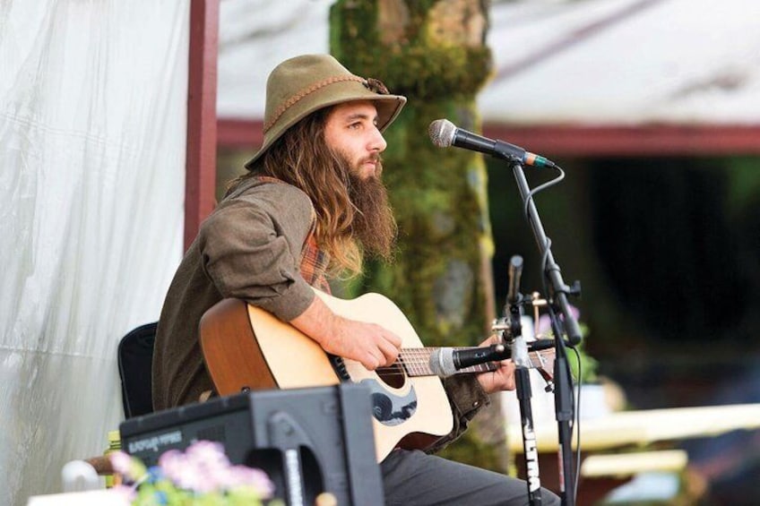 Une personne joue de la guitare acoustique sur scène, avec un microphone et un haut-parleur devant elle. 3