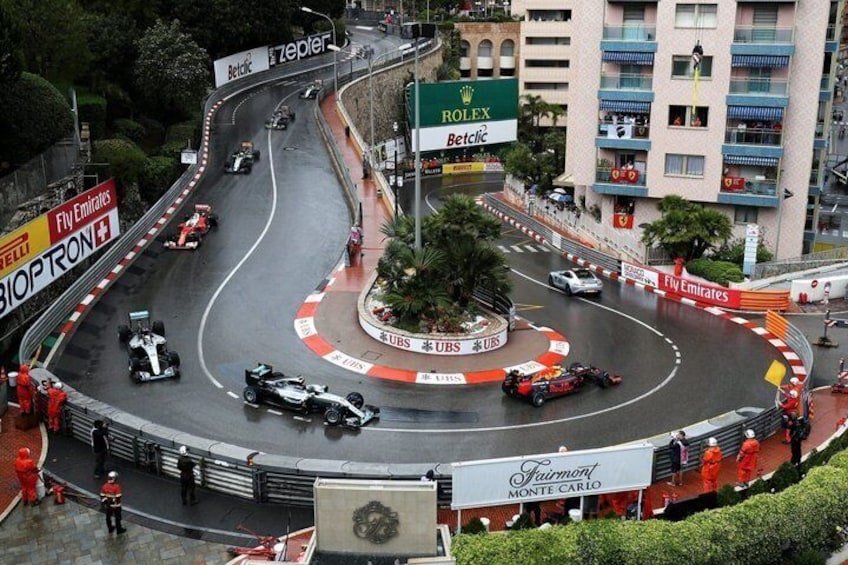 A Formula 1 race track with cars, a Rolex sign, and Fly Emirates advertisements. 2