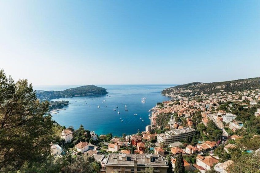 A coastal town with buildings, a clear blue sea, and boats. 1