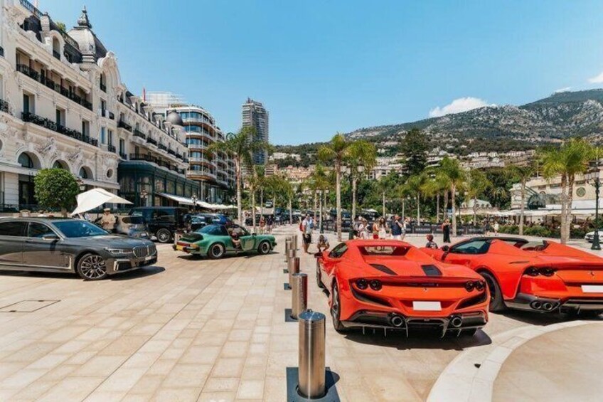 A street with parked sports cars, palm trees, and historic buildings. 3