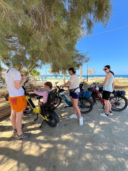 A group of people near a beach with bicycles and a scooter. 4