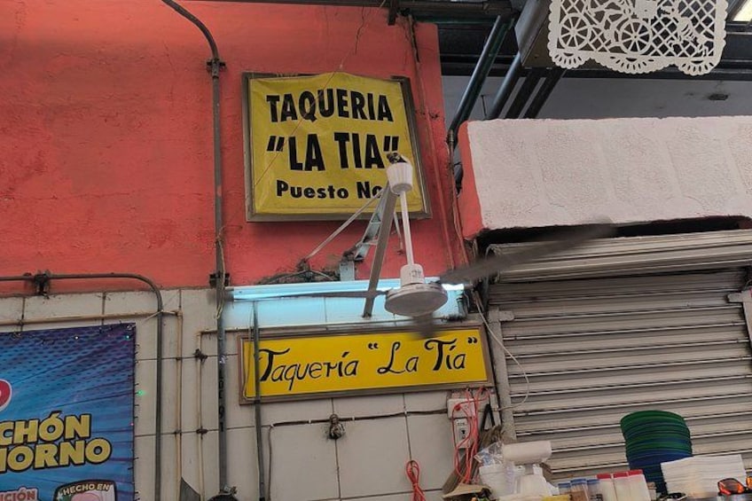 Ein Gebäude mit einem Schild, auf dem 'Taquería 'La Tia' Puesto Norte' steht, und einem Schild darunter. 3