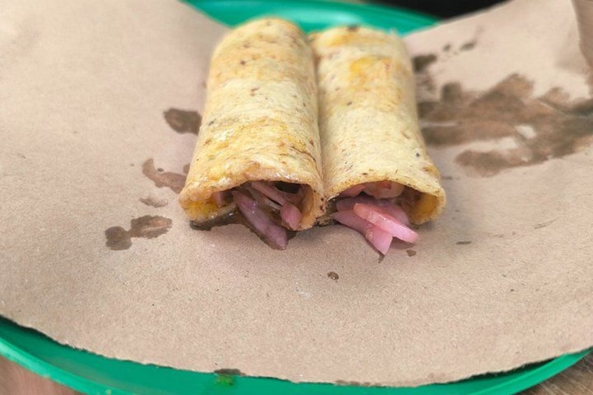 Ein Burrito mit Fleisch und Zwiebeln auf einem Papierteller. 5