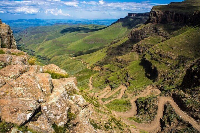 A mountainous landscape with a winding dirt road and rocky outcrops. 1