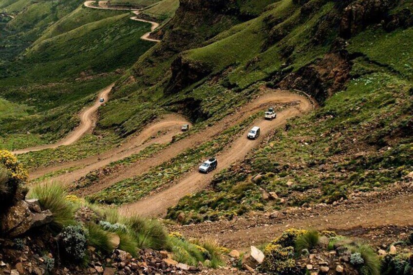 A winding mountain road with vehicles navigating the curves. 5