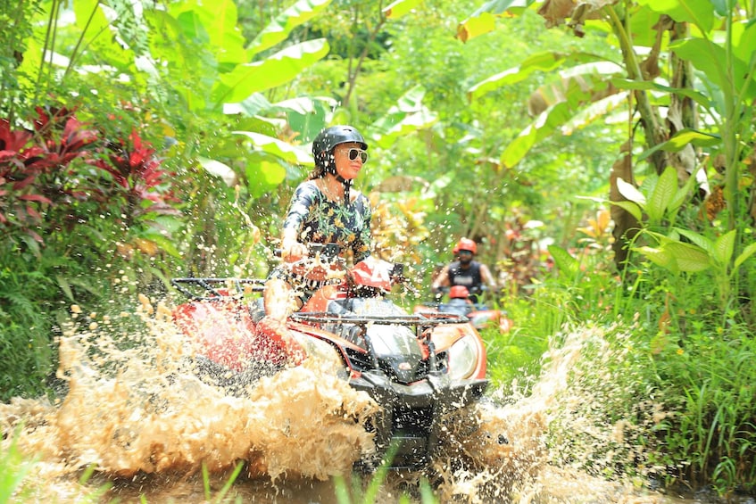A person riding a quad bike through a muddy terrain with splashes of mud around. 5