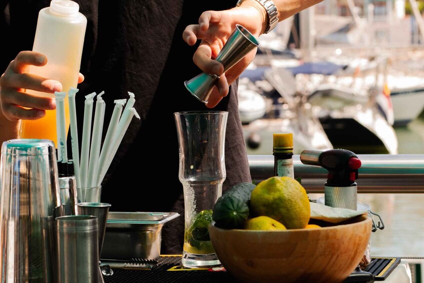 A bartender preparing a drink with a shaker, straws, and a bowl of lemons and limes. 2