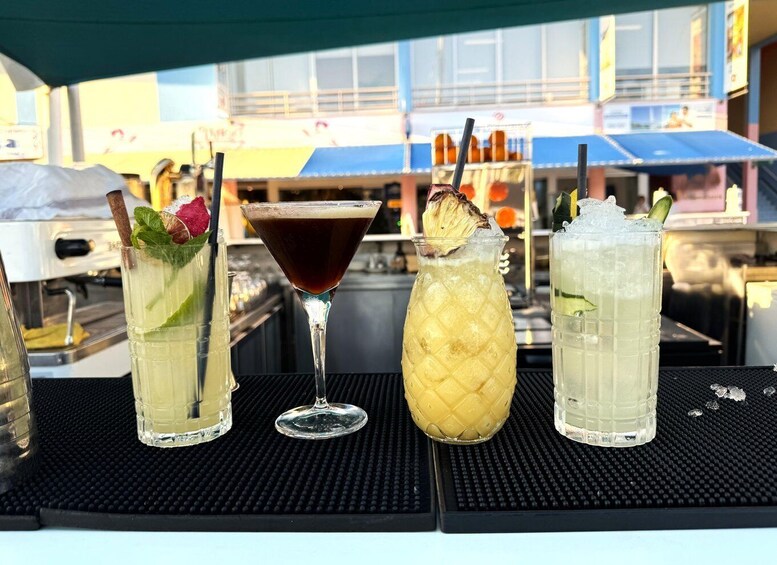Four drinks on a bar counter with a cityscape in the background. 5