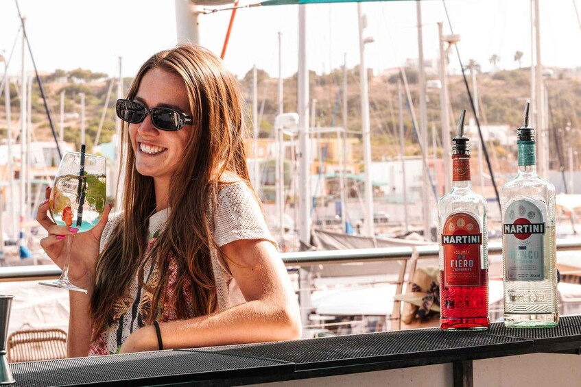 A person holding a cocktail glass at a bar with Martini and Blanco liquor bottles in the background. 3