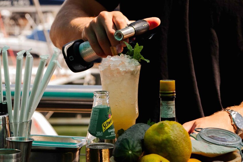 A person pouring a drink into a glass with ice, surrounded by various bottles and glasses. 4