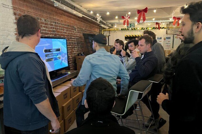 A group of people in a room with a brick wall, a television, and boxes. 4