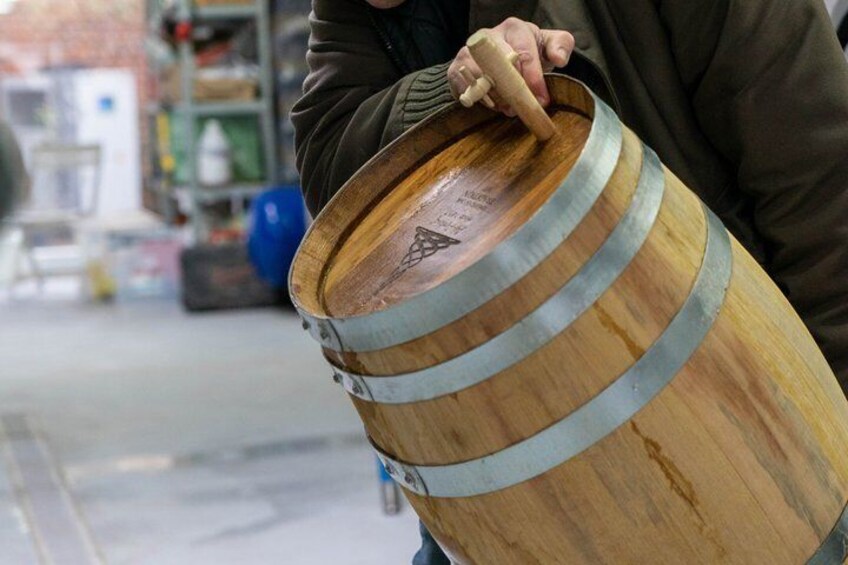 A person holding a wooden barrel with metal bands. 4