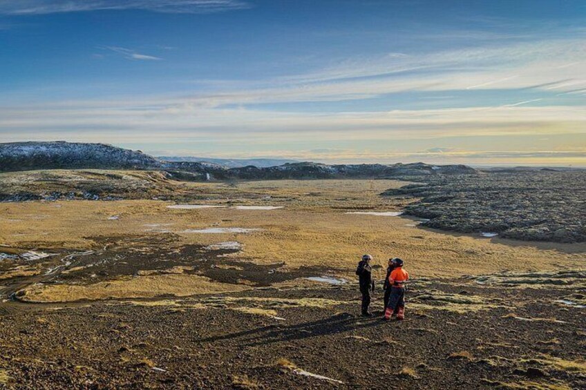 A vast, open landscape with two hikers in the distance. 1
