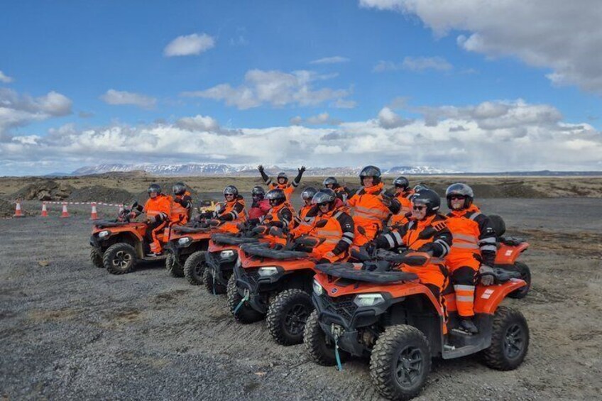 A group of people on orange ATVs in a barren landscape with mountains in the distance. 2
