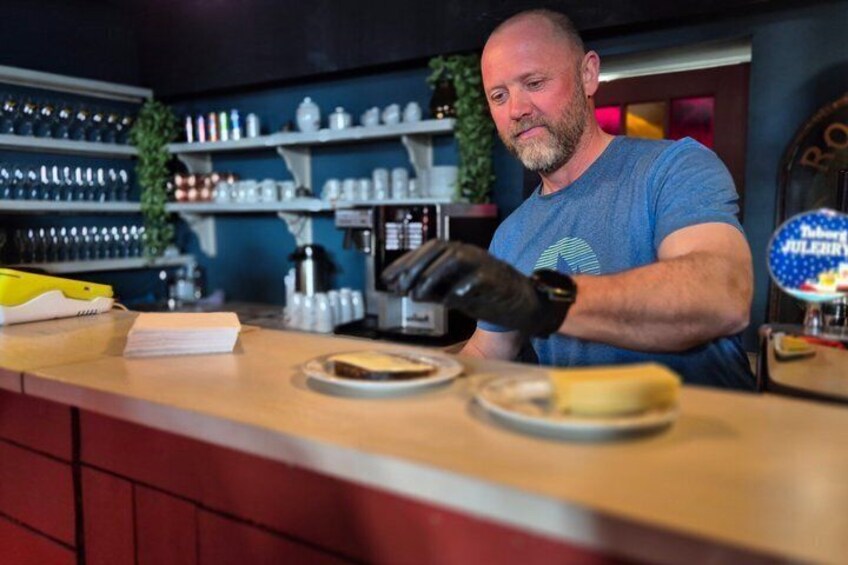 A person preparing food at a counter with various kitchen items and a shelf with utensils. 3