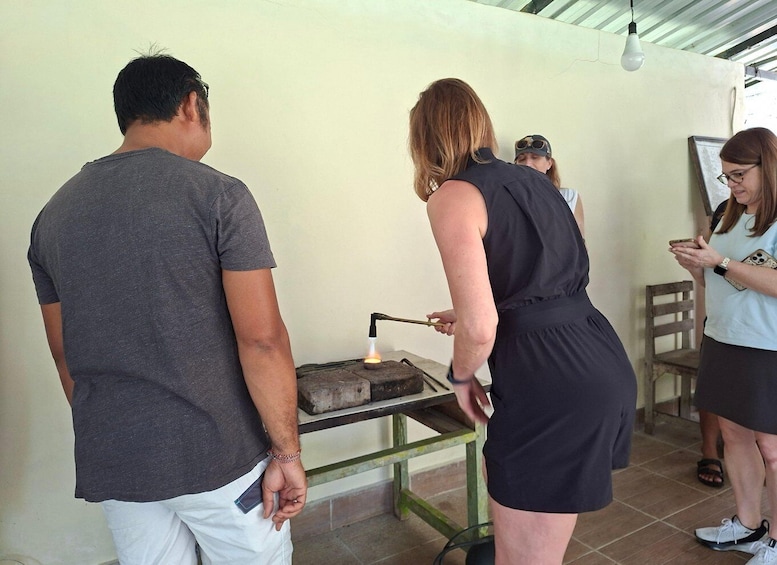 A group of people around a small, open fire with a metal stand. 4