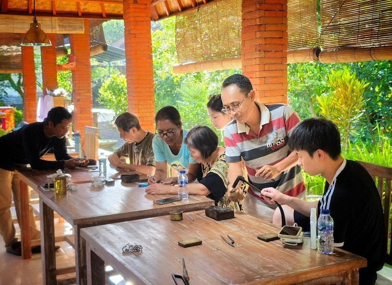 A group of people engaged in a craft activity at a wooden table with tools and materials. 3