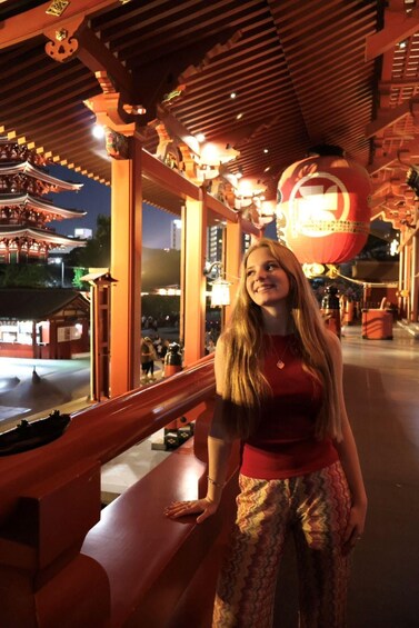 A person standing indoors with traditional architecture, including wooden beams and a red lantern. 1