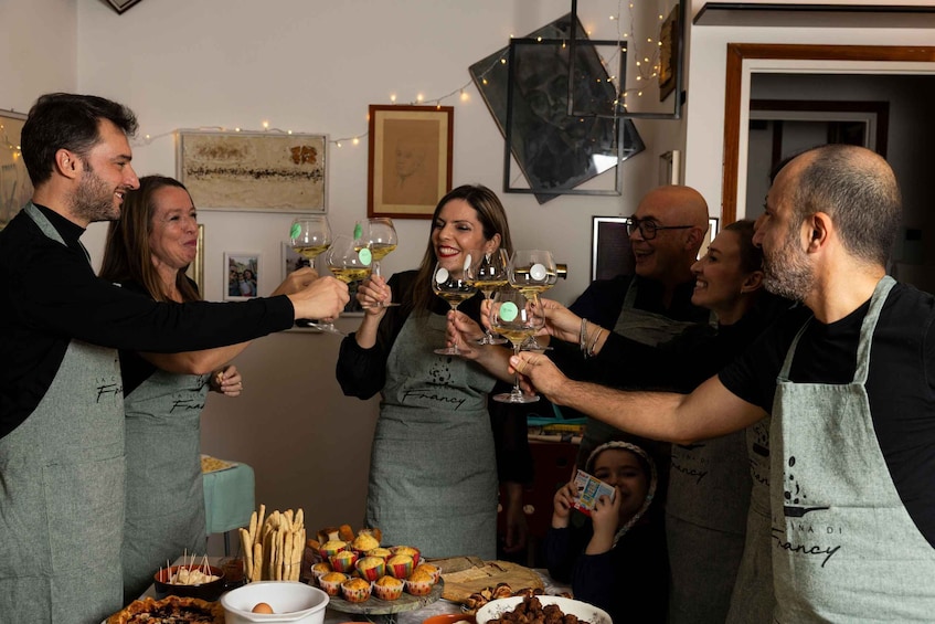 A group of people toasting with wine glasses at a table with food and a decorative wall. 1