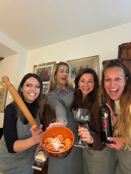 Four people holding food and drinks, with a wooden rolling pin and a bottle of wine. 4