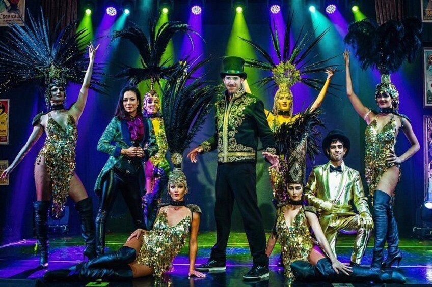 A group of people in elaborate costumes on a stage with spotlights and a blue background. 2