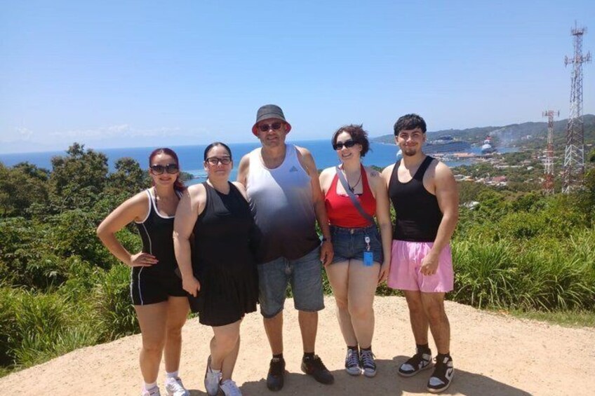 A group of people standing on a dirt path with a coastal view. 3