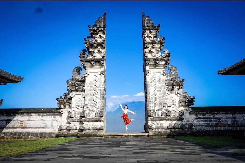 A person jumping through a historic gate with intricate carvings. 1