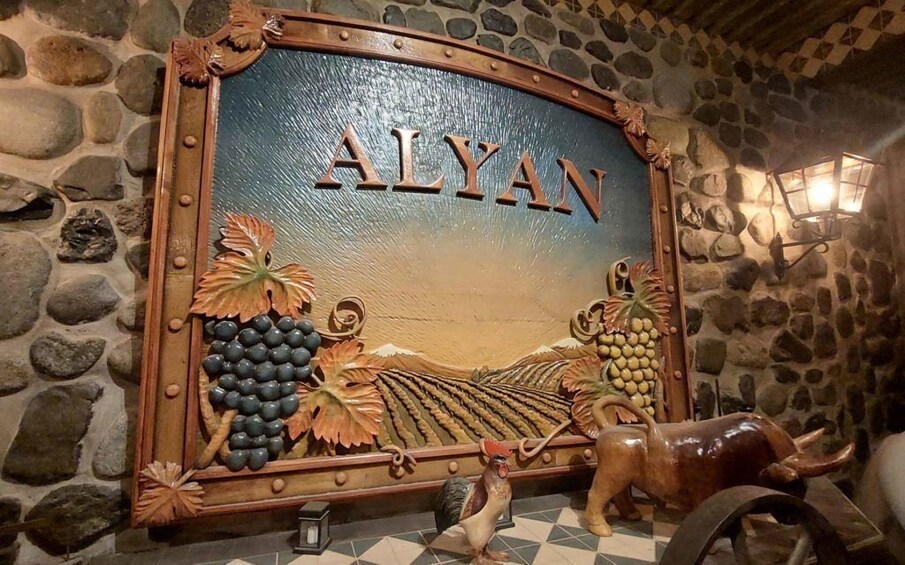 A wooden sign with 'ALYAN' and grapevines, a rooster, and a bull. 4
