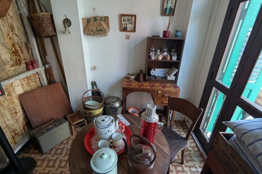 A rustic kitchen with wooden furniture, a dining table set with dishes, and various kitchen utensils. 3