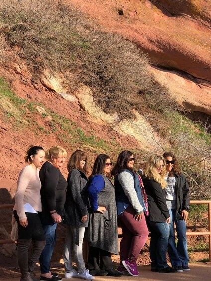 A group of people standing on a path with red rock formations in the background. 1
