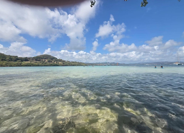 A clear coastal view with a calm sea, distant hills, and a few boats. 2