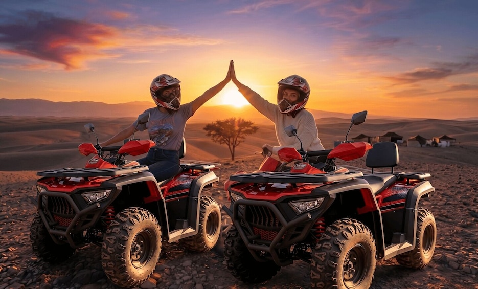 Two people on ATVs with a sunset in the background. 1