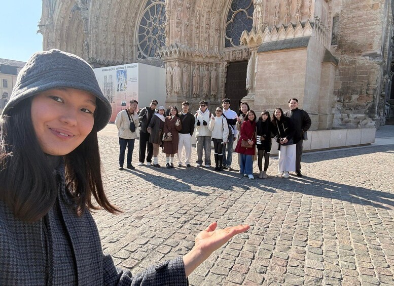 A group of people standing in front of a historic cathedral with intricate stone carvings and large stained glass windows. 1