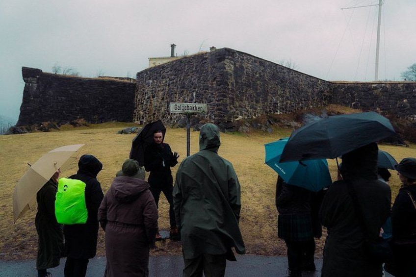Un grupo de personas de pie frente a un muro de piedra con un cartel que dice 'Galgebakken'. 2