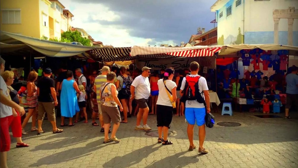 A crowded outdoor market with people browsing stalls. 3