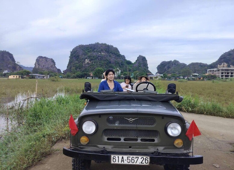 A vehicle with a license plate 61A-567.26 parked near a water body with vegetation and rocky hills in the background. 5