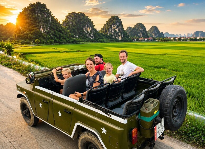 A family in a green jeep on a rural road with fields and mountains in the background. 1