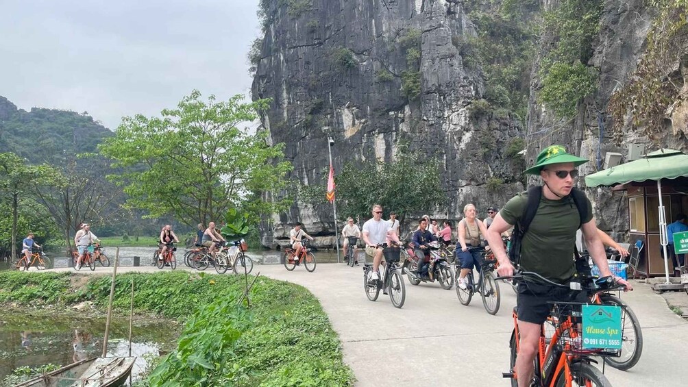 A group of people cycling along a paved path with a mountainous backdrop. 3