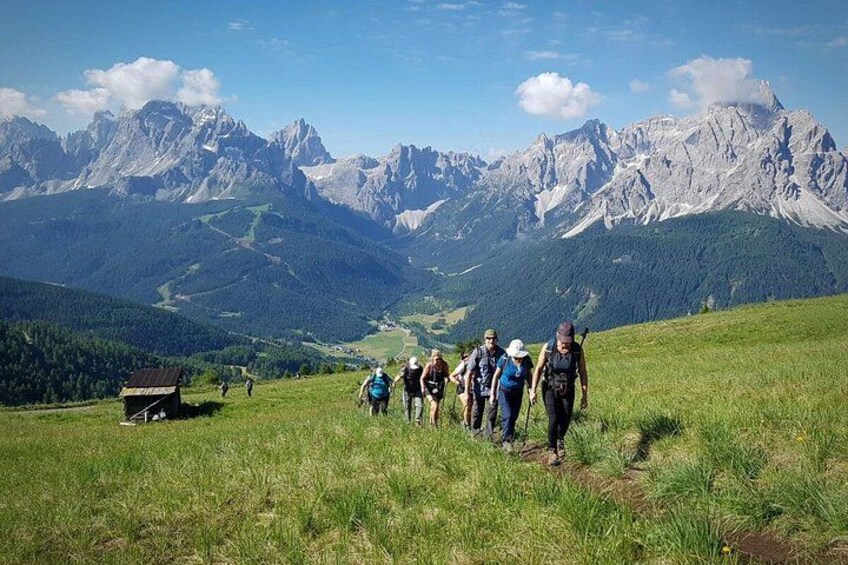 Hikers on a grassy hill with a mountain range in the background. 4