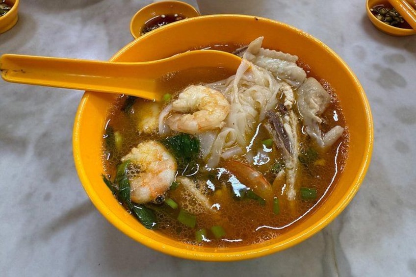 A bowl of soup with noodles, shrimp, and vegetables. 3