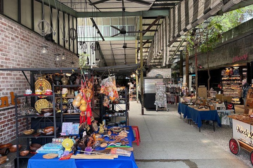 An indoor market with various stalls selling pottery, textiles, and food items. 1