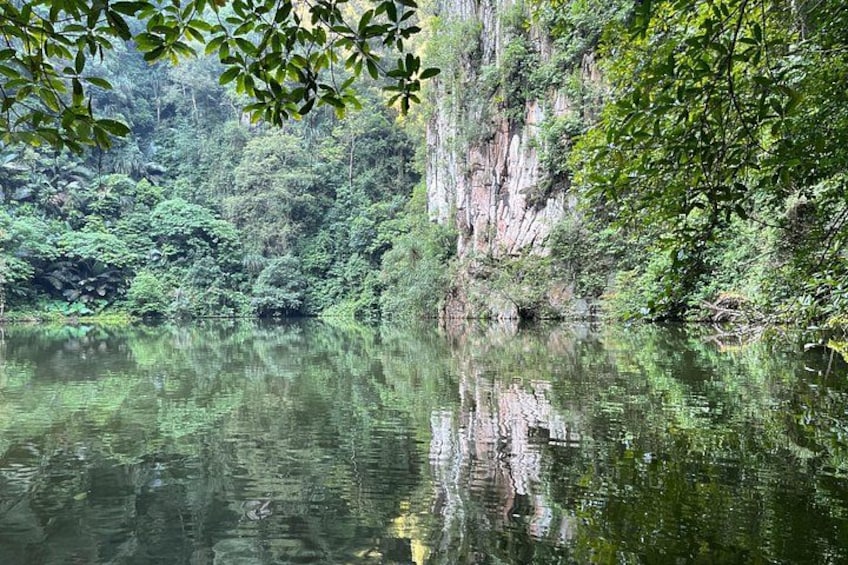 A calm river reflecting the surrounding greenery and cliffs. 2