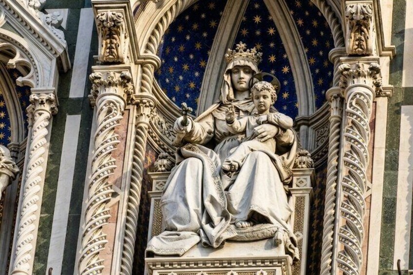 A detailed stone sculpture of a crowned figure holding a child, set within an ornate architectural niche with pointed arches and intricate carvings. 3