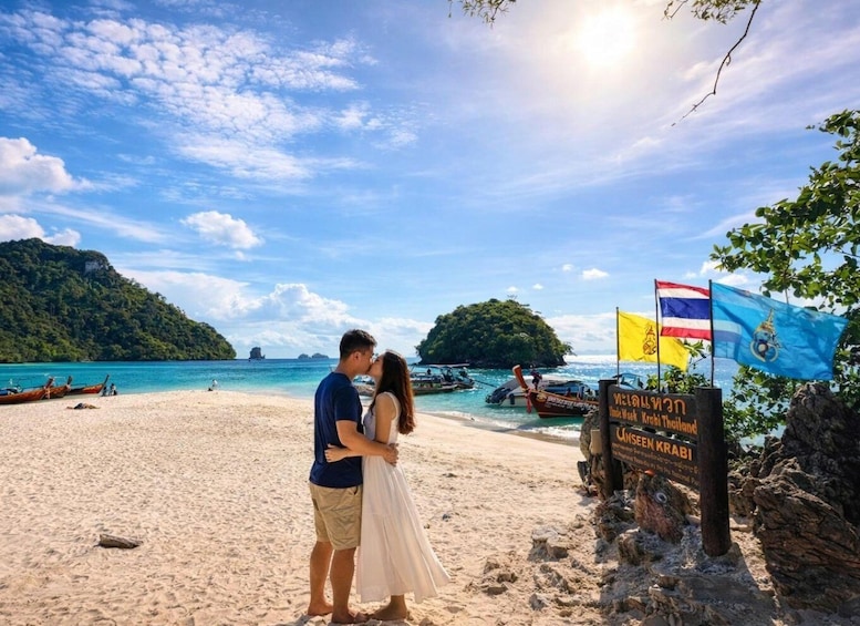 A couple embracing on a beach with boats and flags in the background. 4