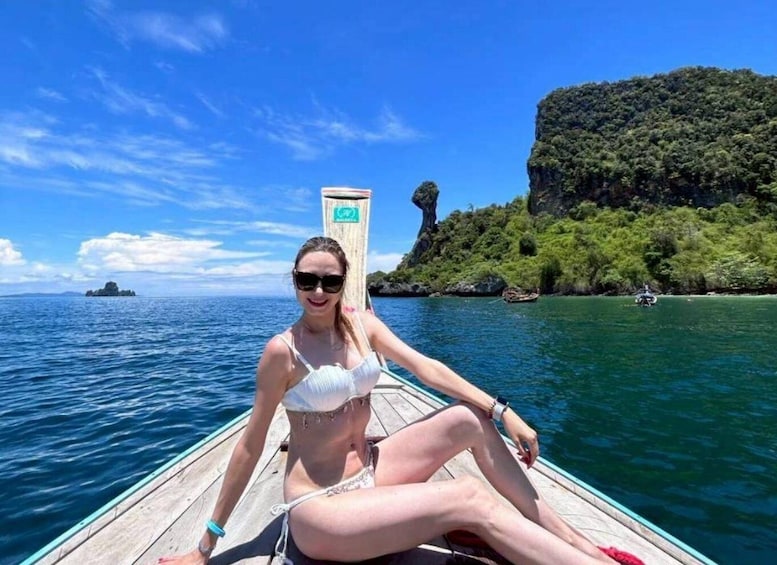 A person on a boat in a clear blue sea with a forested island in the background. 5