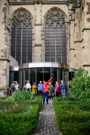 A group of people standing in front of a historic building with large arched windows and a curved entrance. 2