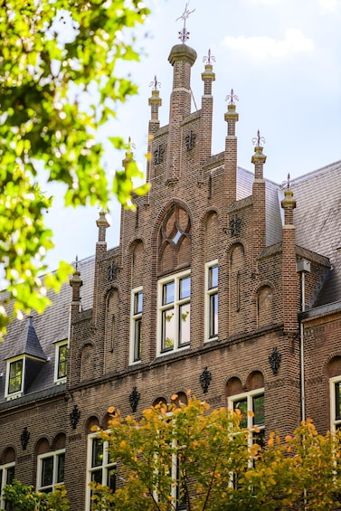 A historic brick building with multiple chimneys, arched windows, and decorative ironwork. 5