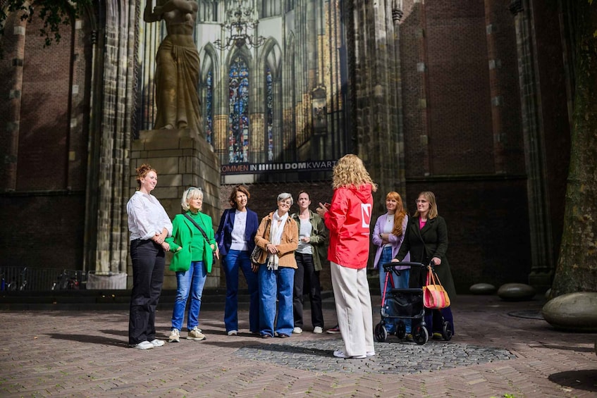 A group of people standing in front of a historic building with a statue and stained glass windows. 3