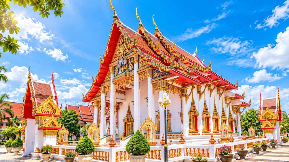 A traditional Thai temple with ornate golden decorations, red and white walls, and a clear blue sky. 4