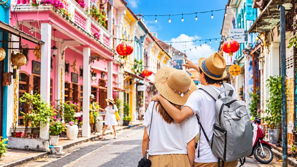 A couple walking down a colorful street lined with traditional buildings, decorated with red lanterns. 3